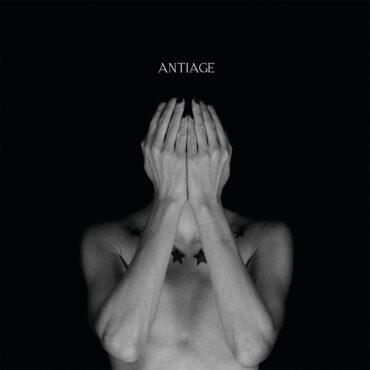 Das Cover des Album "Aphrodisiac Odyssey" von ANTIAGE zeigt Sänger KAA mit nacktem Oberkörper und den Händen vorm Gesicht vor einem schwarzen Hintergrund.